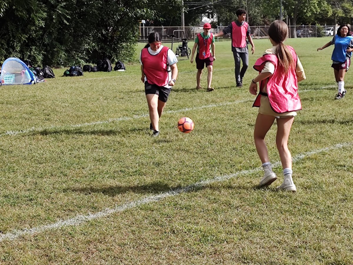 Senior Arianna Tovarez (left) prepares to kick the ball while her teammates cheer her on.