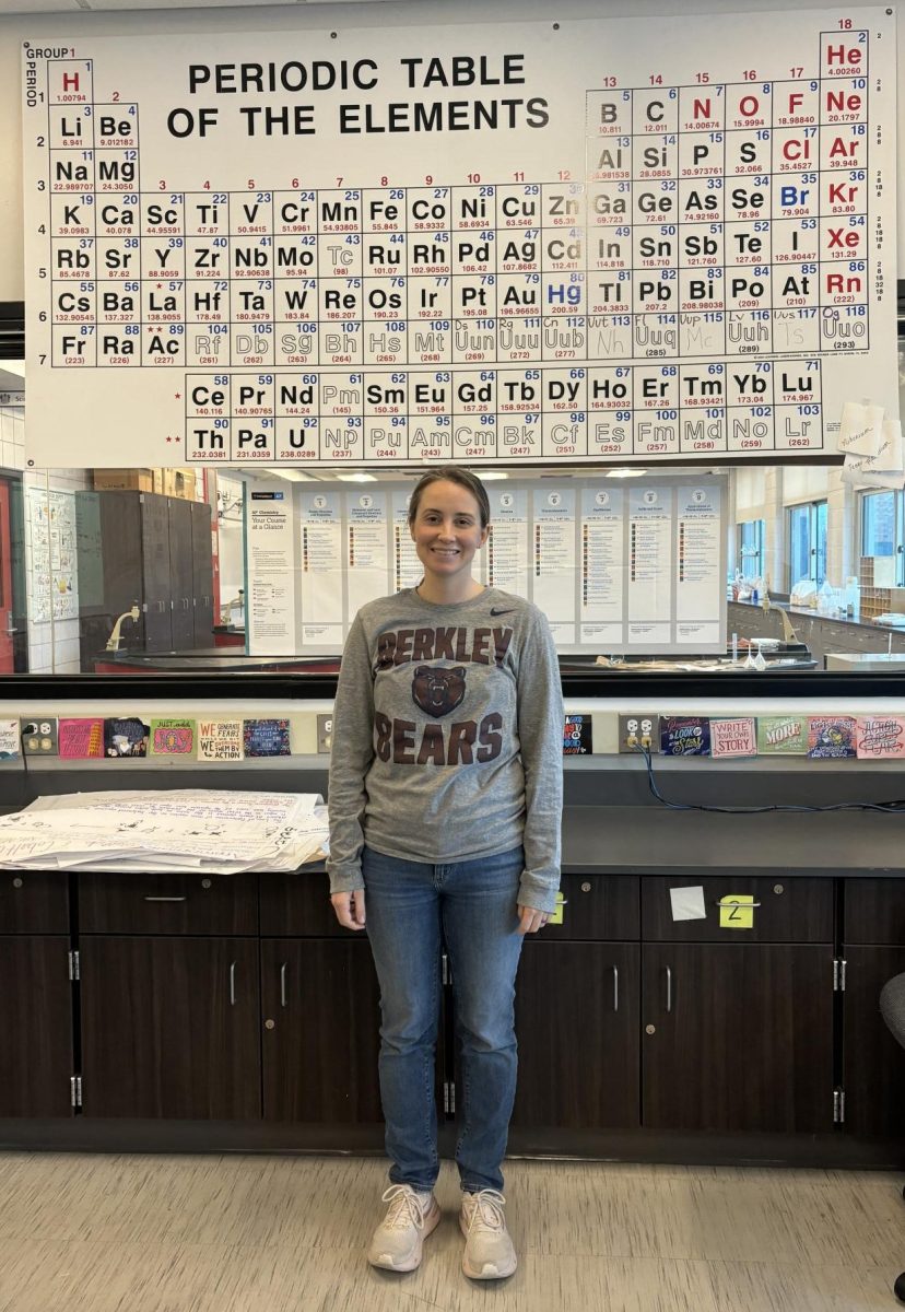 Mrs. Olsen in front of her periodic table.