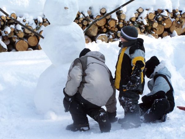 A family making a snowman together on a snowy day.