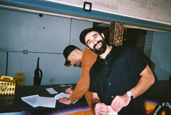 Mark Isakov signing the lease while David Pinkhasov smiles. Photo by Francisco Ramirez
