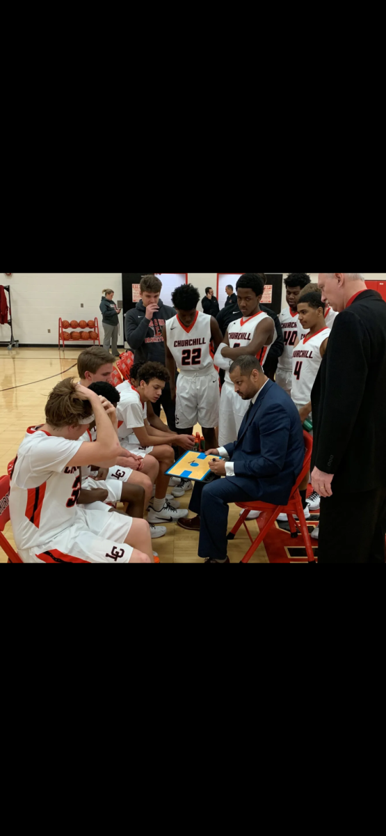 Coach McCulloh in the huddle with Livonia Churchill. Photograph by Andrew Vailliencourt.