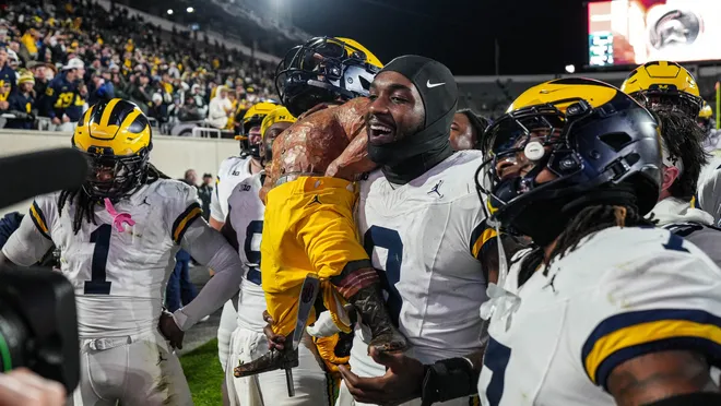 Michigan players hoisting the Paul Bunyan trophy after defeating Michigan State.